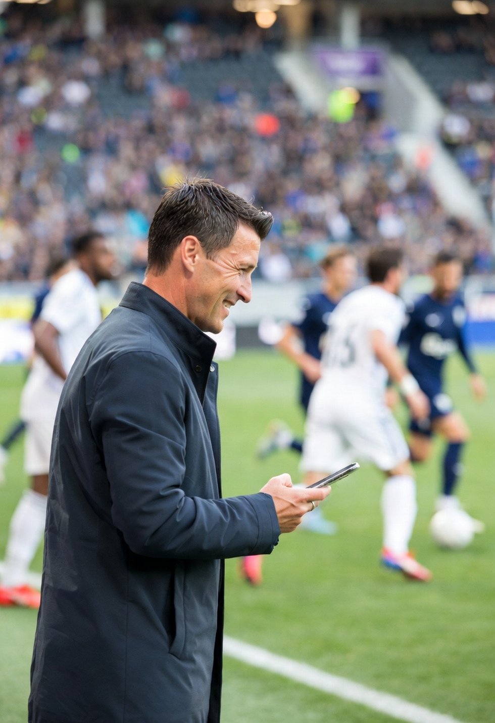Trainer schaut auf sein Smartphone beim Fußballspiel am Spielfeldrand – PLAYARA Live-Spielreport